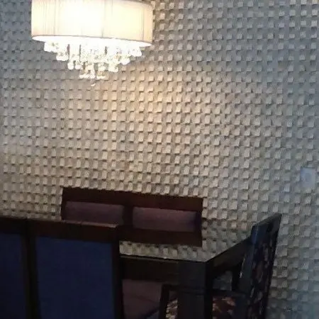 Sala de jantar com parede clara em relevo e lustre de cristal