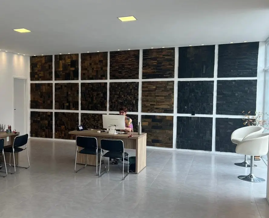 Salão do showroom com mesa de atendimento e painéis de pedra escura